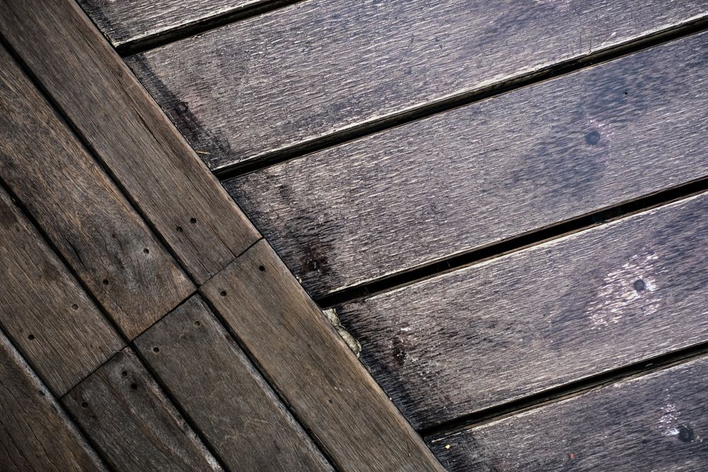 Boards that have taken on water, with open gaps and lifted edges between them.